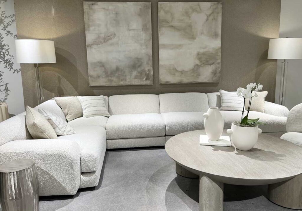 neutral living room abstract art, round wood coffee table, sectional sofa quiet luxury interior design