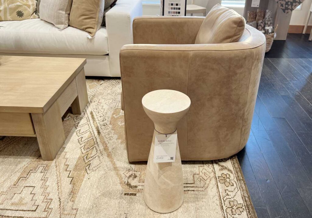 travertine accent table next to leather swivel chair
